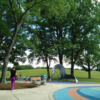 A vibrant park setting with trees and a playground, showcasing people enjoying the outdoors.