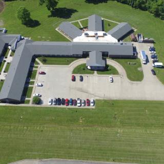 An aerial view of a large facility with a parking lot and surrounding green space.