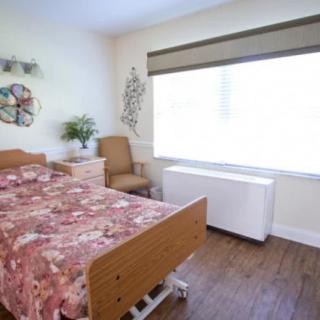 A cozy single bedroom with a hospital bed and a large window.