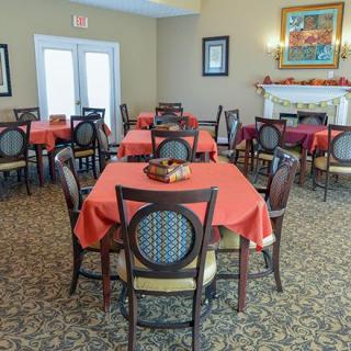 A cozy dining room with tables covered in red tablecloths.