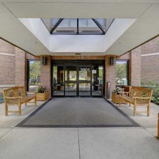 Entrance to a modern building with glass doors and wooden benches.