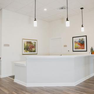 A modern reception area featuring bright walls, pendant lighting, and contemporary artwork on the walls.