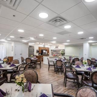 A cozy dining area with neatly arranged tables and chairs, adorned with flowers and napkins.