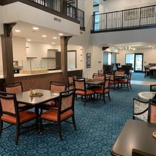 A spacious dining area with multiple tables and chairs, featuring modern architecture and lighting.