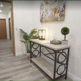 A stylish hallway featuring a console table with decorative items, artwork on the wall, and indoor plants.