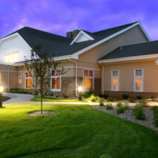 A well-lit house with a landscaped yard during the evening.