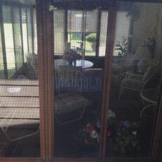 A cozy indoor space with wicker furniture and large windows showcasing a garden view.