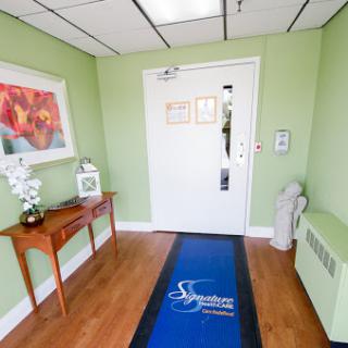 A welcoming foyer featuring green walls, wooden furniture, and decorative elements.