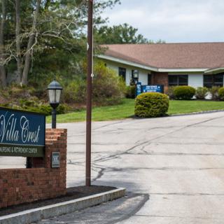 A nursing home with a prominent sign and well-maintained landscaping.