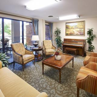 A cozy living room featuring comfortable seating, a piano, and elegant decor.