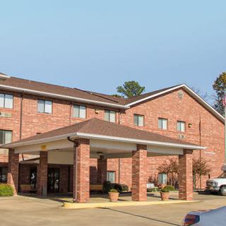 A brick exterior hotel with a covered entrance and landscaped surroundings.