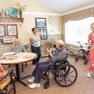 A group of seniors interacting in a cozy nursing home setting.