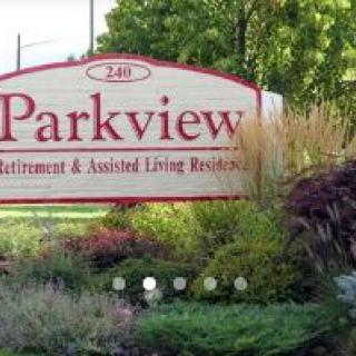 A welcoming sign for Parkview Retirement & Assisted Living Residence surrounded by lush greenery.