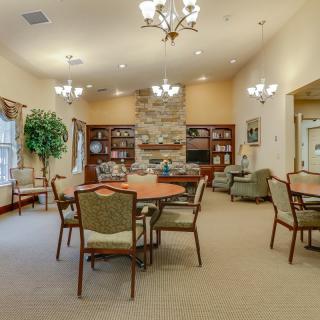 A spacious living room with multiple seating areas, a central fireplace, and bookshelves.