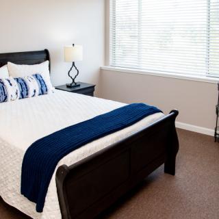 A minimalist bedroom with a bed, nightstand, and large window.