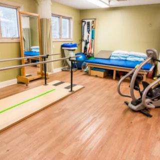 A physical therapy room equipped with exercise equipment and parallel bars.