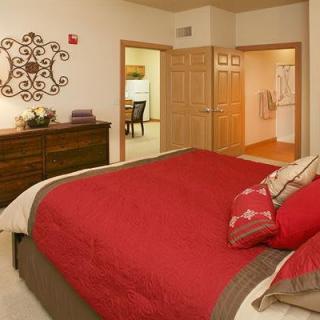 A cozy bedroom with a red comforter and stylish decor.
