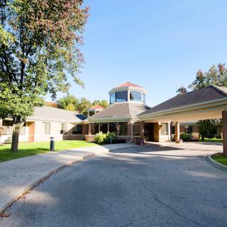An inviting residential building with a well-maintained driveway and lush greenery.