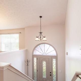 A bright interior entrance with a staircase, chandelier, and arched window above the front door.