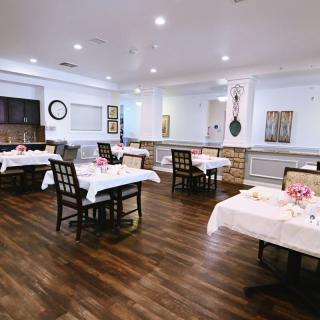 An elegant dining area with neatly arranged tables and chairs on a wooden floor.