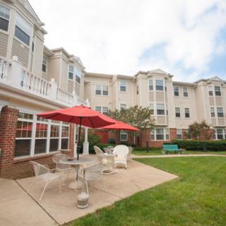 A view of a residential building with an outdoor patio area featuring tables and a red umbrella.