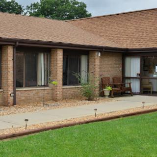 A modern brick residential building with a well-maintained lawn and patio area.