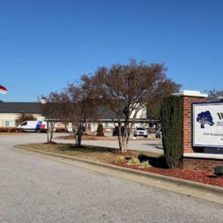A view of a building with a sign and flag surrounded by trees on a clear day.
