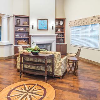 A cozy living room with a central fireplace, surrounded by bookshelves and featuring elegant wood flooring.