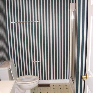 A bathroom featuring striped wallpaper and a toilet.