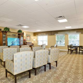 A well-arranged living room featuring multiple chairs, a television, and large windows that let in natural light.
