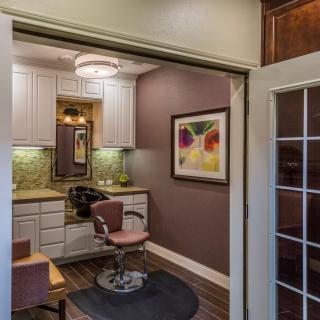 A cozy hair salon interior with a styling chair, mirror, and colorful wall art.