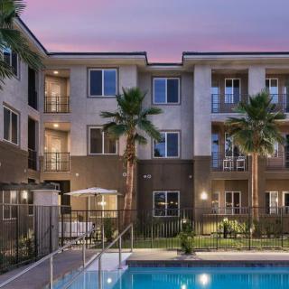 Evening view of an apartment building with a pool and palm trees.