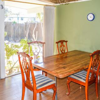 A cozy dining room with a wooden table and chairs, featuring a green wall and large window.