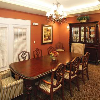 A formal dining room featuring a wooden table with matching chairs, a chandelier, and a china cabinet against warmly colored walls.