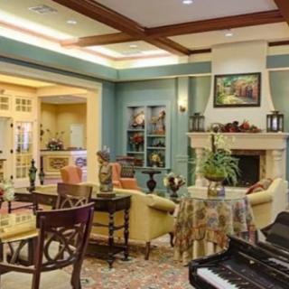 A cozy living room featuring a fireplace, elegant furniture, and a grand piano.