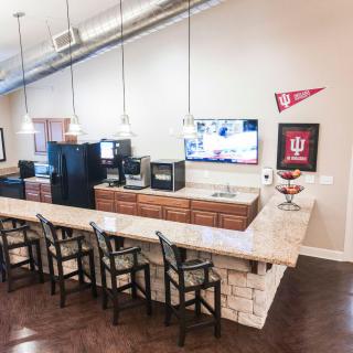 A modern kitchen area featuring a long counter with bar stools, pendant lighting, and university-themed decorations.