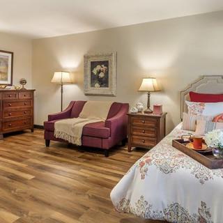 A cozy bedroom with elegant decor, featuring a comfortable armchair, wooden furniture, and warm lighting.