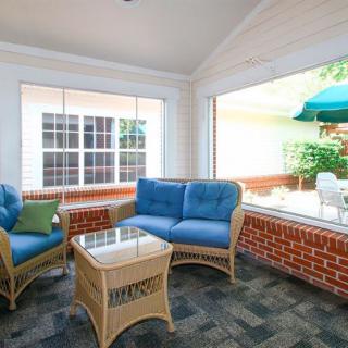 A cozy sunroom with wicker furniture and blue cushions overlooks a bright patio area.