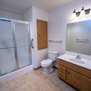 A modern and clean bathroom featuring a shower, toilet, sink, and ample lighting.