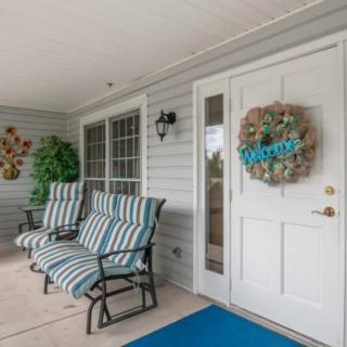 A welcoming porch with striped chairs and a decorative wreath on the door.
