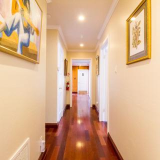 A brightly lit hallway with wooden floors and decorative paintings on the walls.