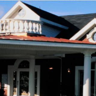 A house with classical architectural elements including columns and a small balcony.