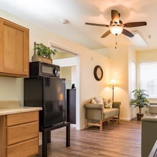 A cozy open-plan kitchen and living area with wooden flooring, a ceiling fan, and comfortable seating.