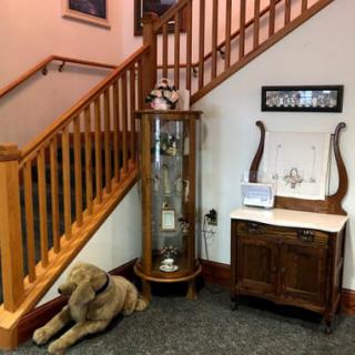 A cozy corner featuring a wooden staircase, display cabinet, and a decorative dog statue.
