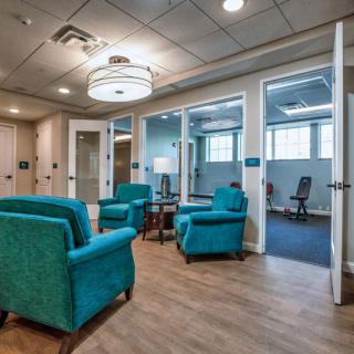 A modern waiting area featuring teal chairs and a bright, comfortable atmosphere.