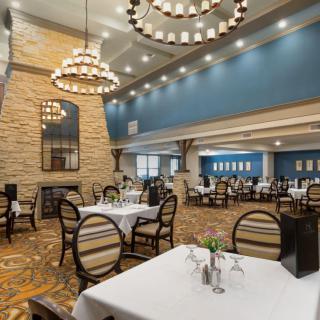 An elegant dining area featuring chandeliers and neatly arranged tables and chairs.