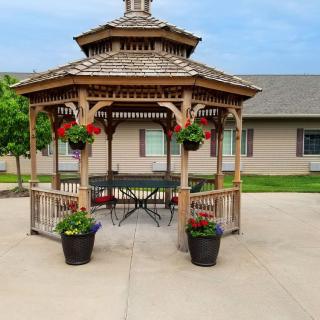 A charming gazebo with hanging baskets and flower pots, set on a spacious patio.