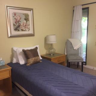 A cozy bedroom with a single bed, bedside tables, and a decorative chair.