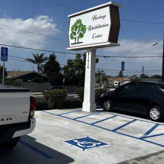 A parking lot with designated handicap parking spaces, featuring a business sign for Heritage Rehabilitation Center.