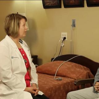 A doctor in consultation with a patient in a hospital room.